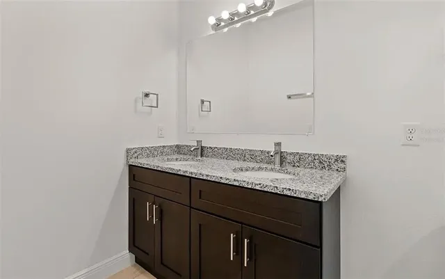 a bathroom with a granite countertop sink toilet mirror and bathtub