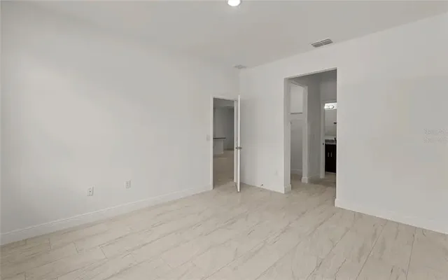a view of an empty room with wooden floor and closet