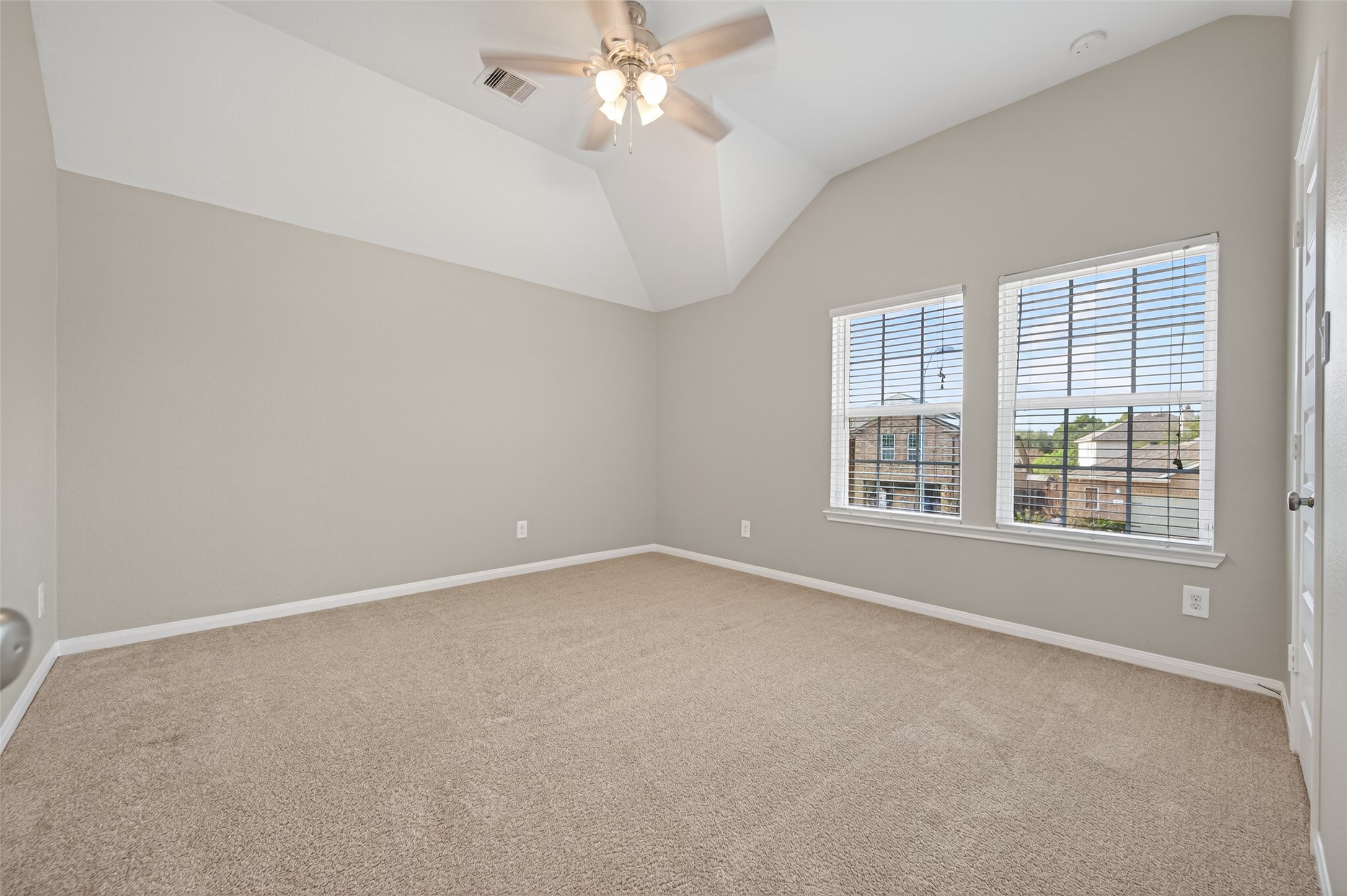 7003 Bristol Memorial Drive Spring, TX 77379 - Photo 30 of 40 Generously sized secondary bedroom featuring soaring vaulted ceilings that enhance the open, airy feel. Large windows provide abundant natural light and neighborhood views, while neutral tones and plush carpeting create a versatile space ready to fit a variety of needs. This well-proportioned bedroom offers flexibility and comfort, complementing the thoughtful layout of this Spring TX home.