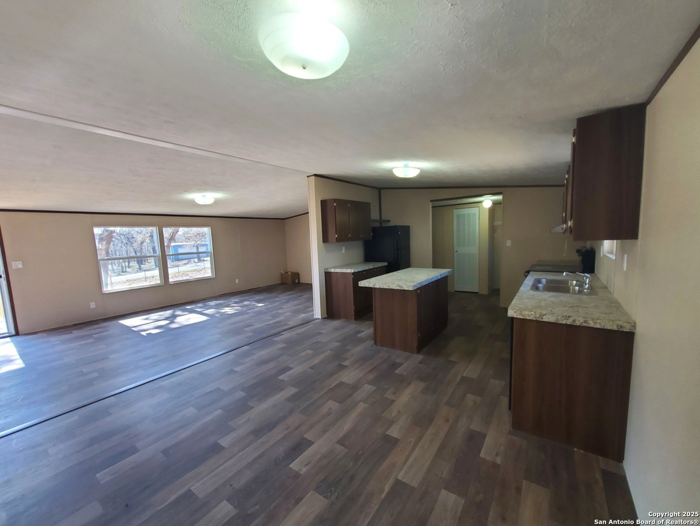 61 Post Oak Road, Unit A La Vernia, TX 78121 - Photo 3 of 11 a open kitchen with kitchen island a sink dishwasher a stove and a refrigerator with wooden floor