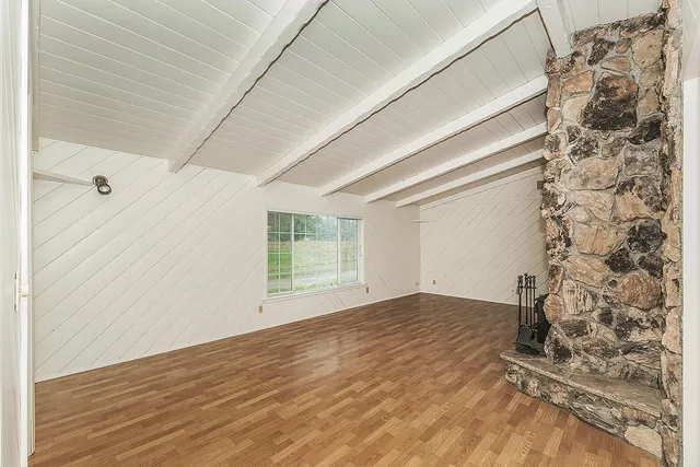 a view of empty room with wooden floor and fireplace