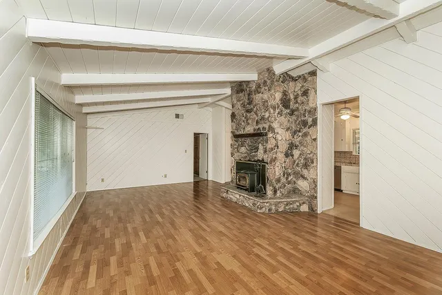 a view of a livingroom with wooden floor a fireplace and window