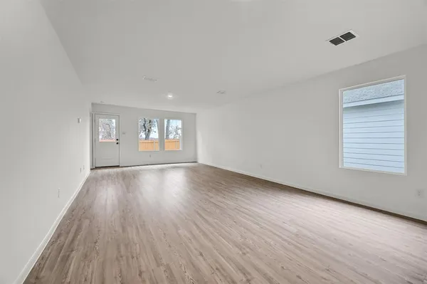 a view of an empty room with window and wooden floor
