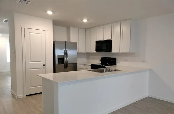 a kitchen with a refrigerator and a stove top oven