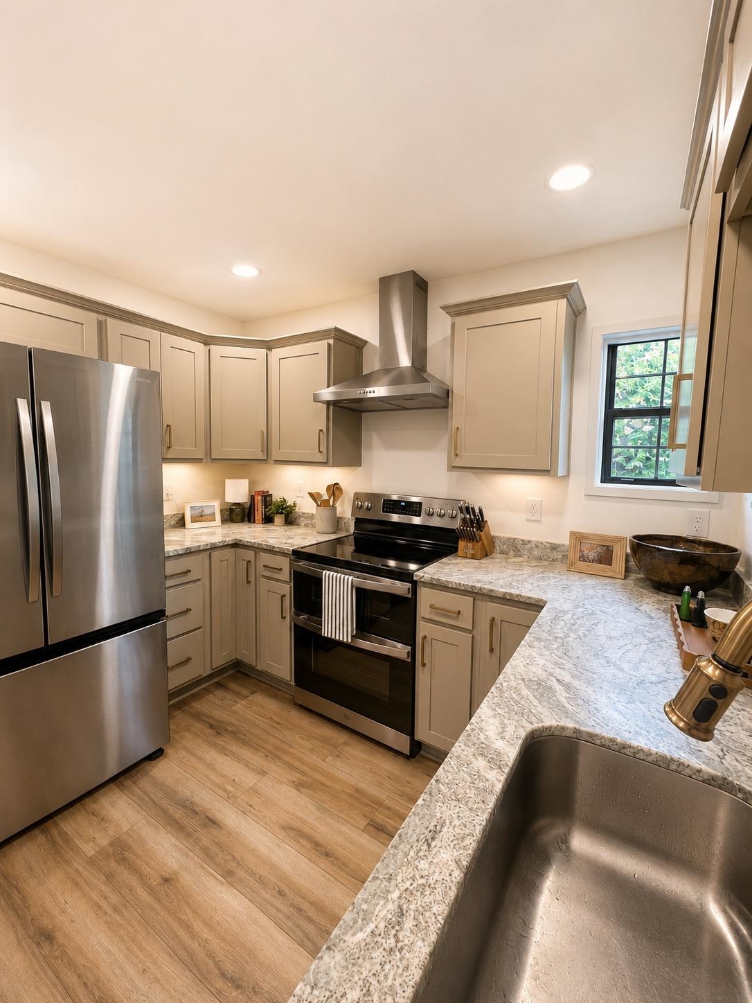 470 Rich Road Somerville, TN 38068 - Photo 21 of 40 Contemporary kitchen featuring wood-finish flooring, light-toned cabinetry with crown molding, stainless steel appliances, and mottled countertops