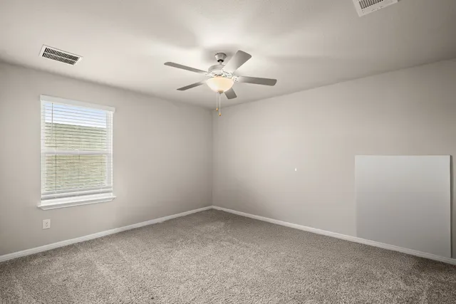 an empty room with windows and fan