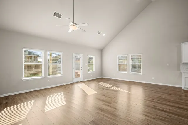 a view of an empty room with a window and wooden floor