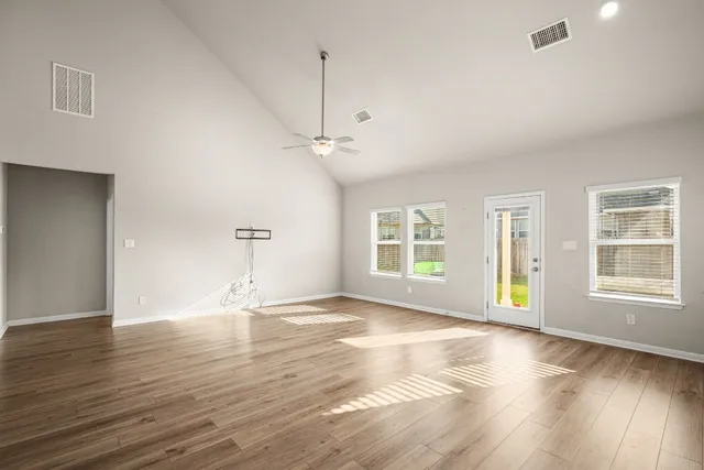 an empty room with wooden floor and windows