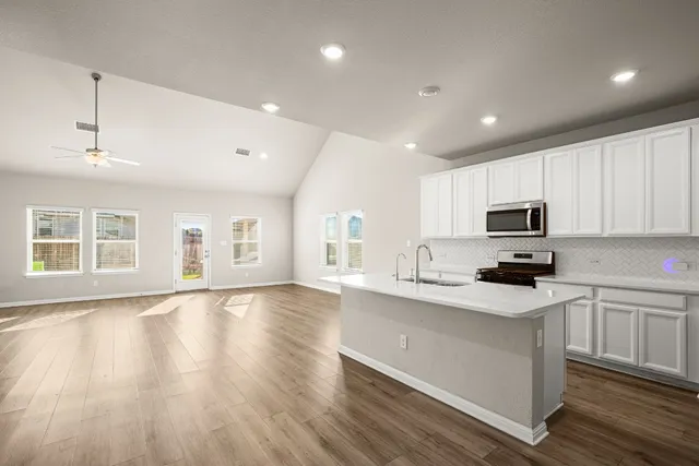 a kitchen with granite countertop a sink cabinets and wooden floor