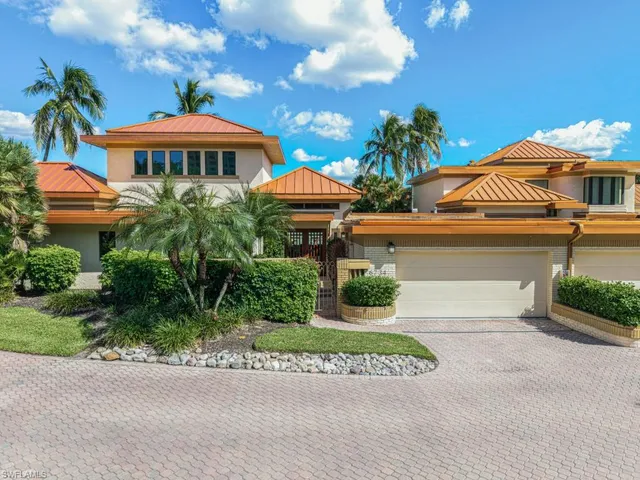 a view of a table and chairs under an umbrella in front of house