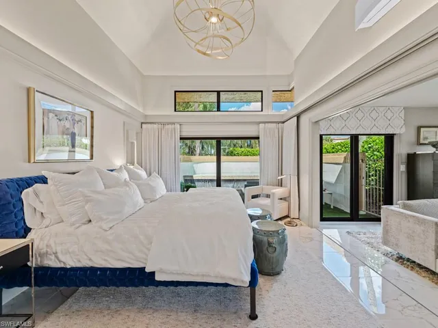 a large white bed sitting in a bedroom next to a window