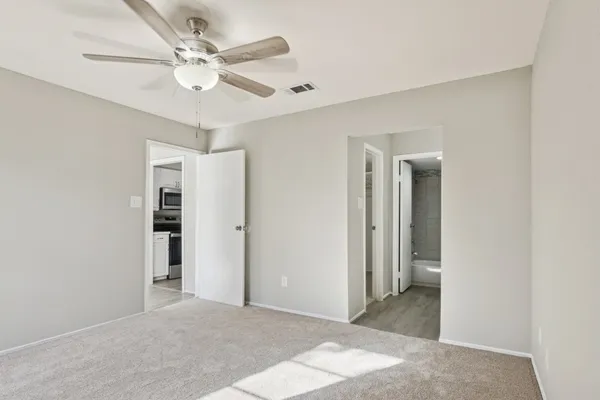 an empty room with windows and fan