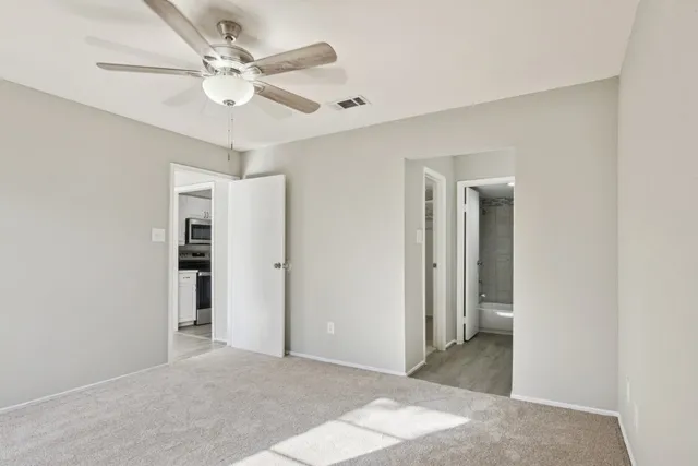 an empty room with windows and fan