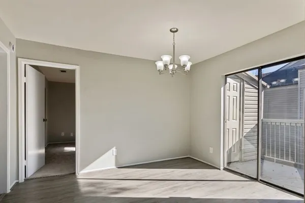 a view of a hallway with wooden floor and chandelier