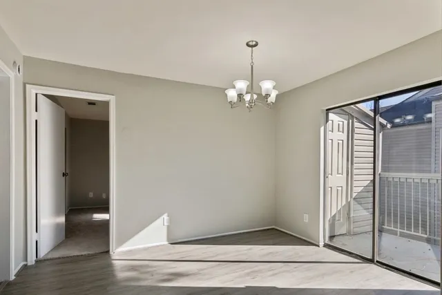 a view of a hallway with wooden floor and chandelier