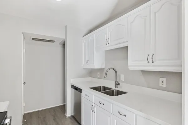 a kitchen with white cabinets a sink and dishwasher
