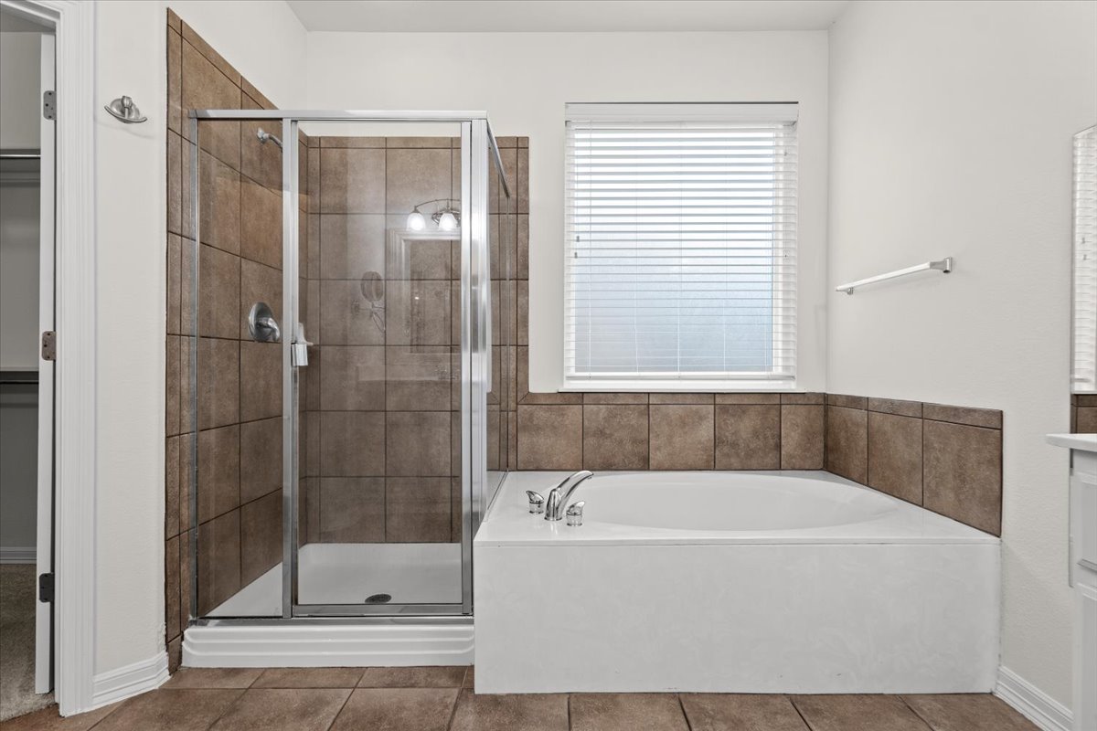 2304 Village View Loop Pflugerville, TX 78660 - Photo 26 of 40 A well-appointed bathroom features a glass-enclosed shower and a deep soaking tub, perfect for relaxation.