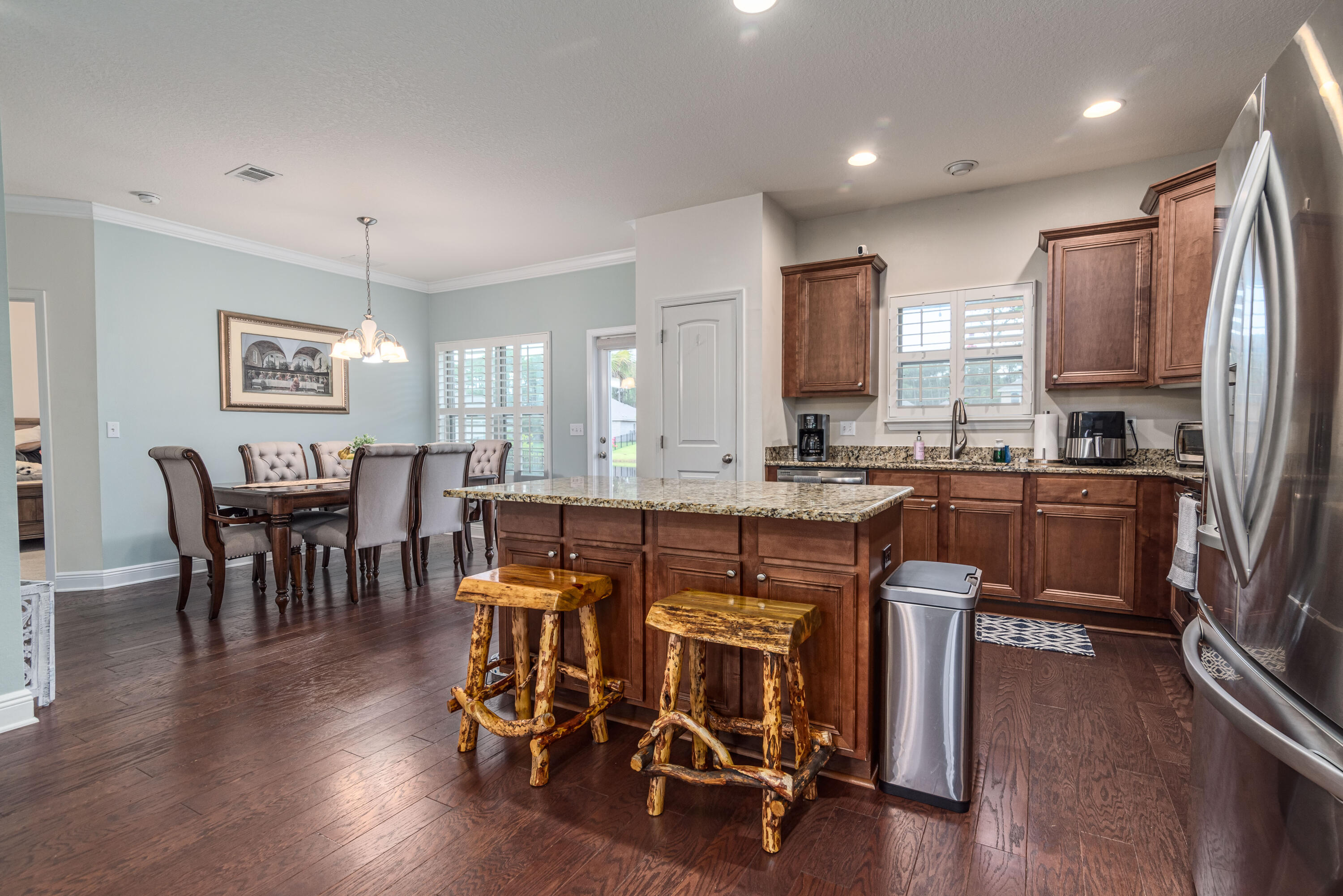 142 Pin Oak Loop Santa Rosa Beach, FL 32459 - Photo 32 of 56 a open kitchen with stainless steel appliances granite countertop a stove a refrigerator a kitchen island a dining table and chairs with wooden floor