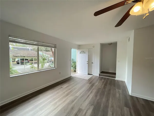 a view of an empty room with wooden floor and a window
