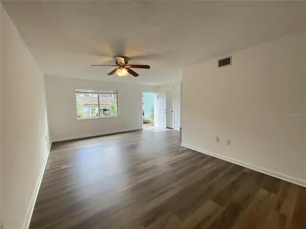 an empty room with wooden floor and windows
