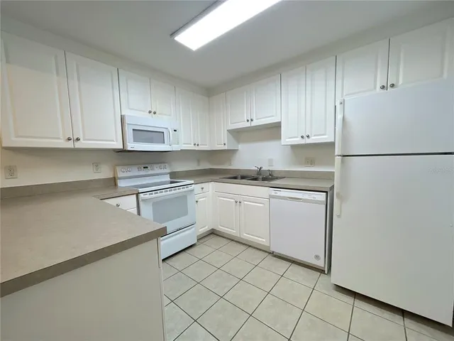 a kitchen with granite countertop white cabinets and white appliances