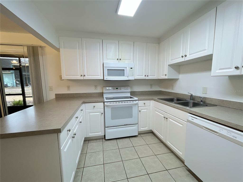 501 Southwest 75th Street, Unit C4 Gainesville, FL 32607 - Photo 17 of 37 a kitchen with granite countertop white cabinets and white appliances