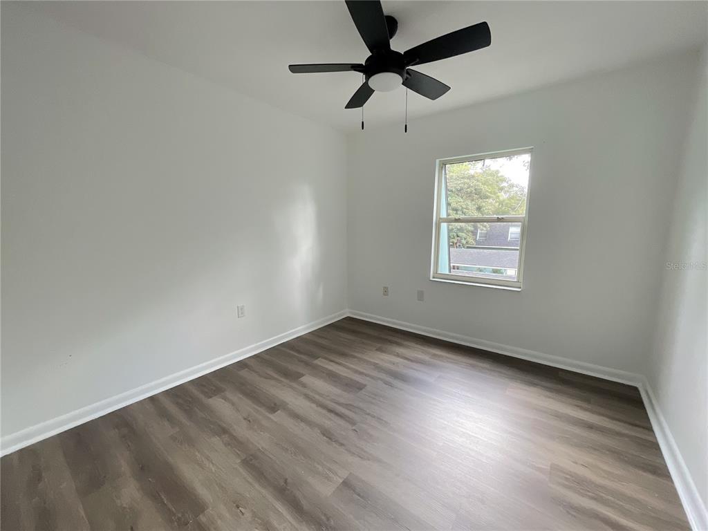 501 Southwest 75th Street, Unit C4 Gainesville, FL 32607 - Photo 4 of 37 an empty room with wooden floor fan and windows