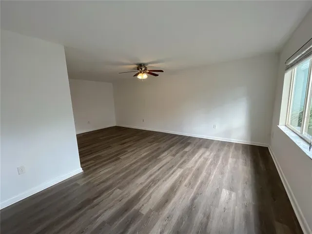 an empty room with a window and a ceiling fan