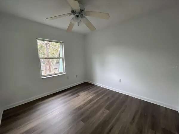 an empty room with a window and a ceiling fan