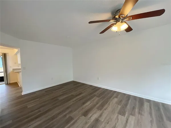 an empty room with wooden floor fan and windows