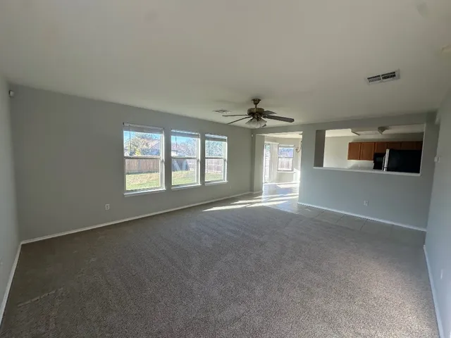 a view of a big room with windows and chandelier fan