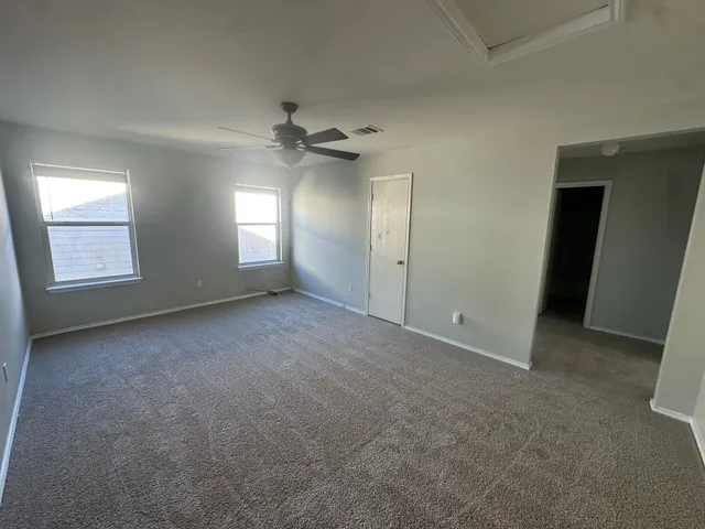 an empty room with windows and ceiling fan