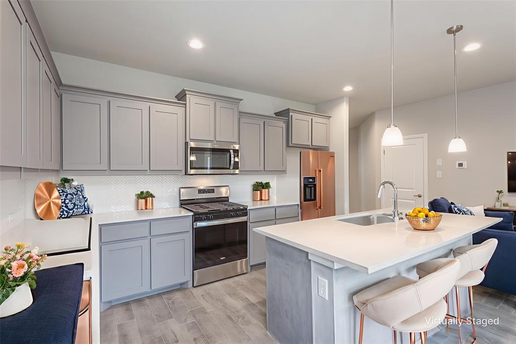 14621 Bootes Drive Haslet, TX 76052 - Photo 18 of 40 Kitchen featuring gray cabinets, stainless steel appliances, a kitchen breakfast bar, an island with sink, and wood tiled floors