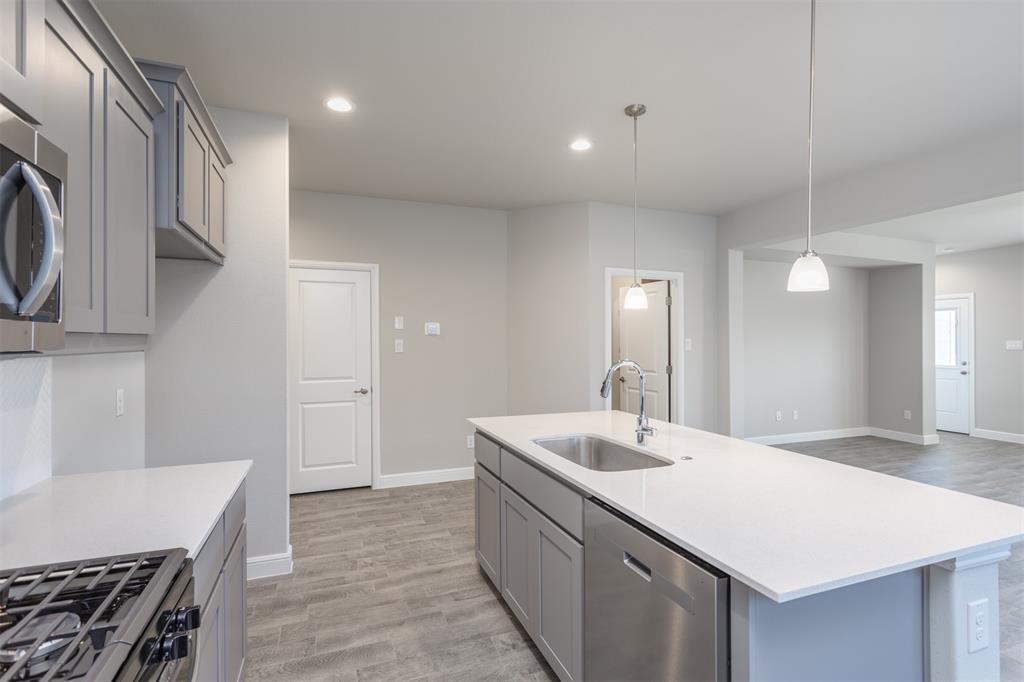 14621 Bootes Drive Haslet, TX 76052 - Photo 20 of 40 Kitchen with gray cabinets, appliances with stainless steel finishes, light wood-style floors, hanging light fixtures, and light stone counters
