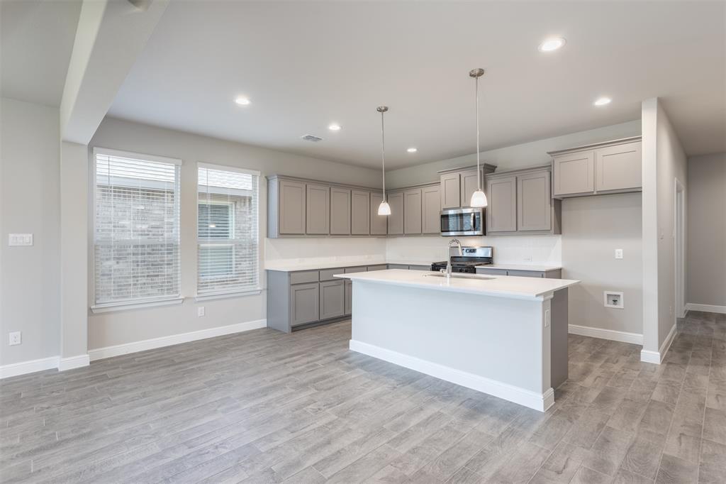 14621 Bootes Drive Haslet, TX 76052 - Photo 22 of 40 Kitchen with gray cabinetry, a center island with sink, pendant lighting, stainless steel appliances, and light wood-type flooring