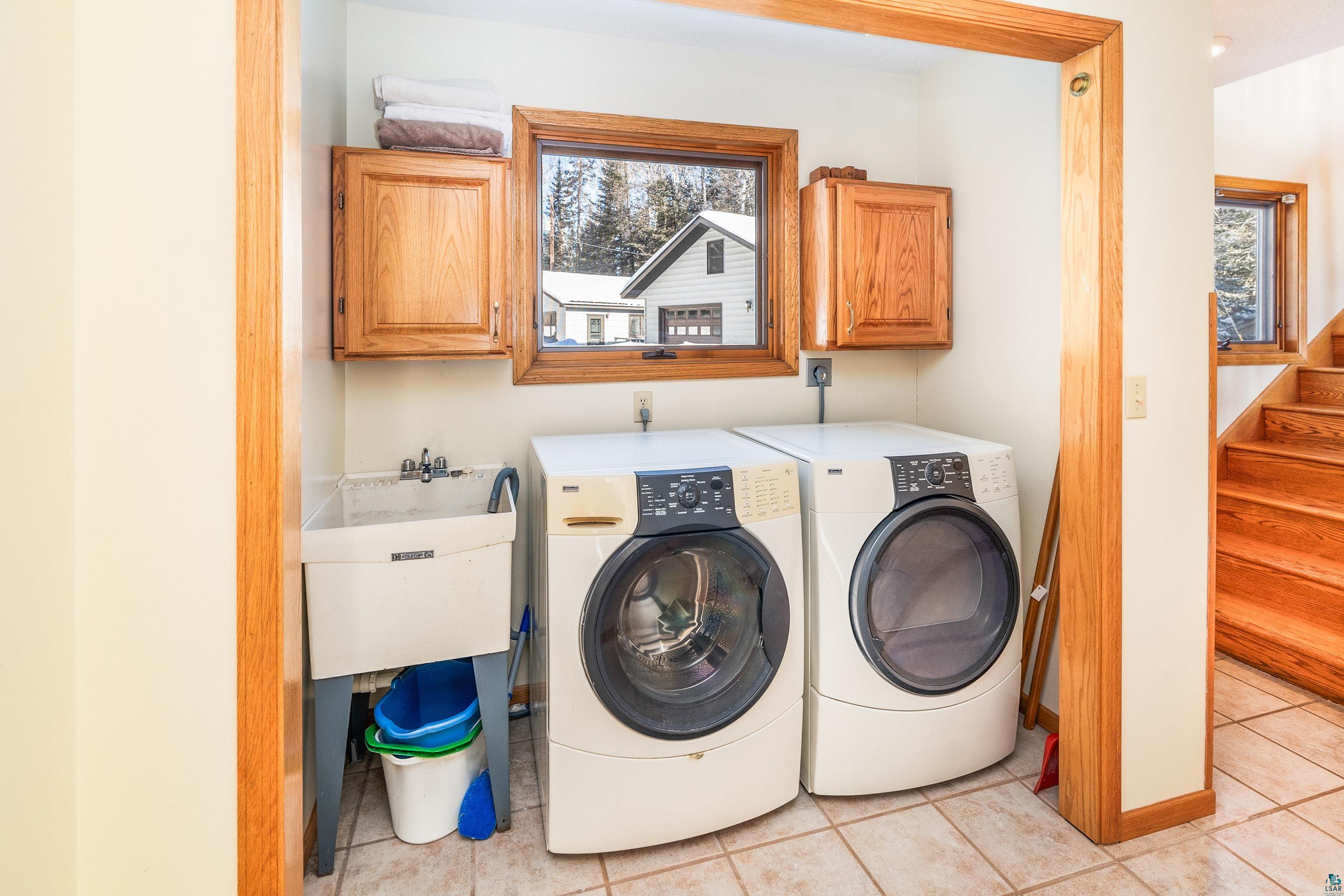 1480 Devil Track Road Grand Marais, MN 55604 - Photo 28 of 46 Laundry area with cabinets, light tile patterned flooring, sink, and independent washer and dryer