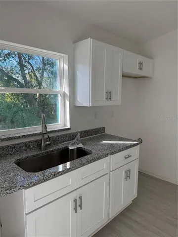 a kitchen with granite countertop white cabinets and sink