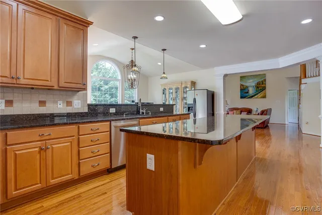 a kitchen with stainless steel appliances granite countertop a sink a stove and a wooden floors