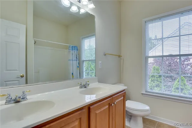 a bathroom with a granite countertop sink toilet a large mirror and a window
