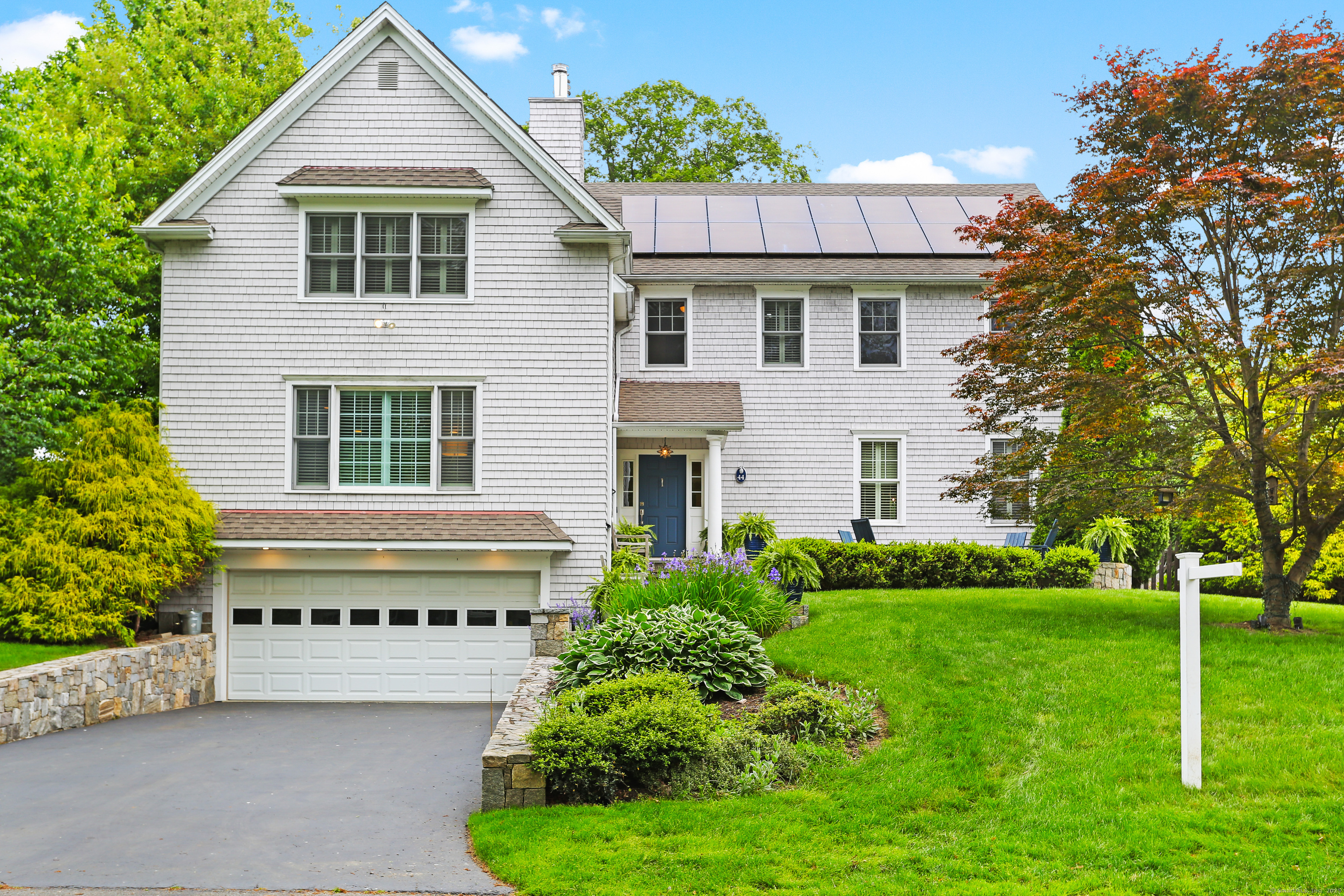 a view of a house with a yard plants and large tree