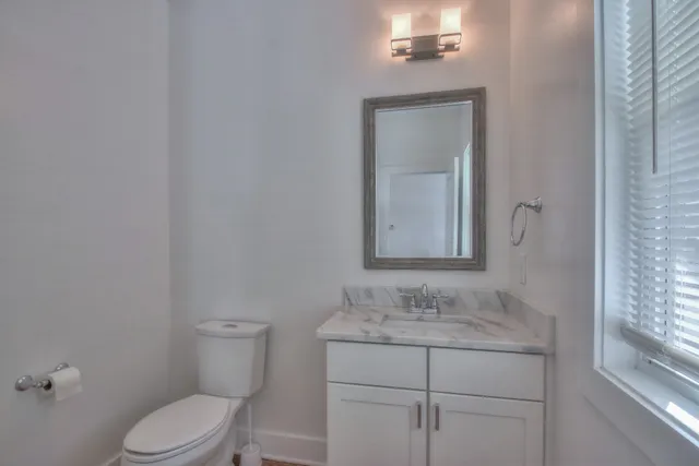 a bathroom with a granite countertop toilet sink and mirror