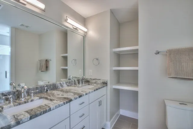 a bathroom with a granite countertop sink two mirror and a shower