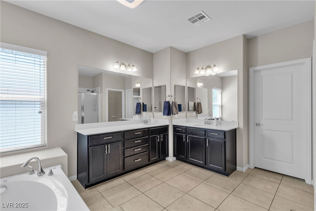 9950 Coyote Echo Court Las Vegas, NV 89166 - Photo 19 of 71 Full bathroom featuring a garden tub, light tile patterned floors, two vanities, and a shower stall