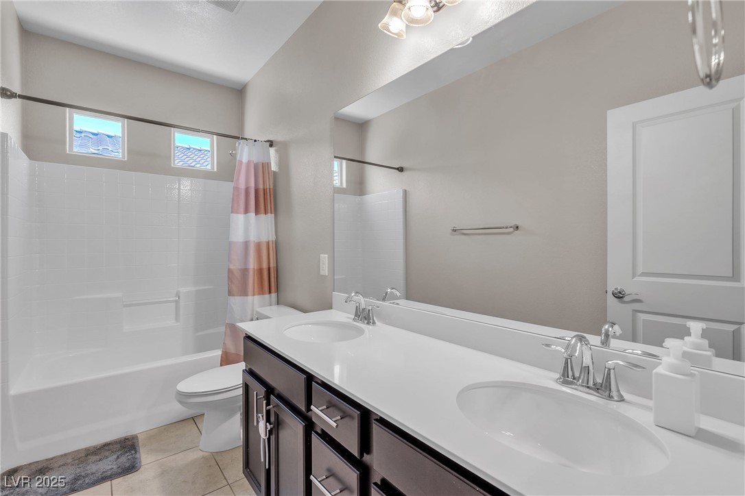 9950 Coyote Echo Court Las Vegas, NV 89166 - Photo 26 of 71 Bathroom with shower / bath combination with curtain, double vanity, and light tile patterned floors
