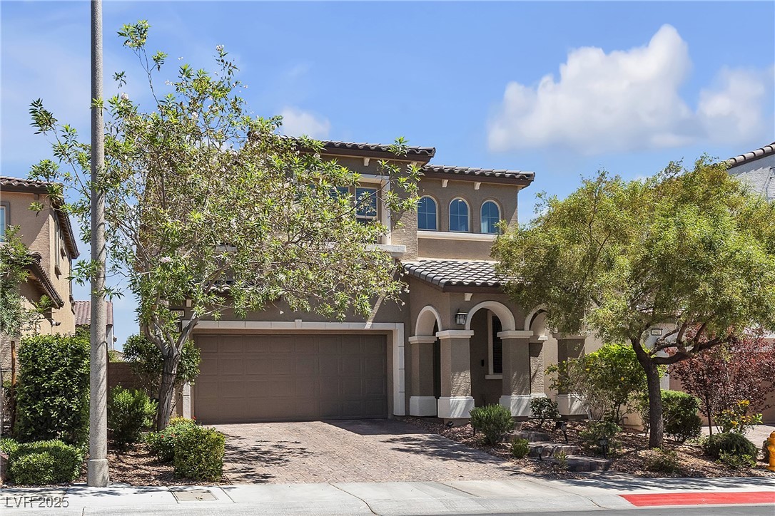 9950 Coyote Echo Court Las Vegas, NV 89166 - Photo 3 of 71 Mediterranean / spanish-style home with a tiled roof, decorative driveway, stucco siding, and an attached garage