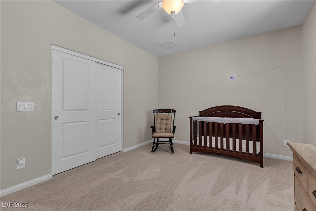 9950 Coyote Echo Court Las Vegas, NV 89166 - Photo 41 of 71 Bedroom featuring a nursery area, light carpet, and ceiling fan