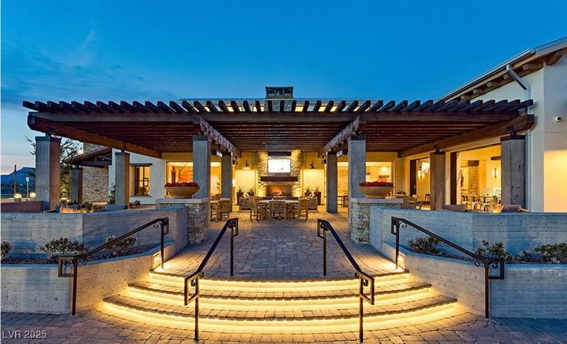 9950 Coyote Echo Court Las Vegas, NV 89166 - Photo 66 of 71 Patio terrace at dusk featuring a patio area, exterior kitchen, a pergola, and outdoor dining space