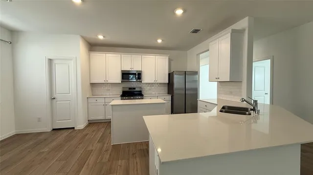a kitchen with refrigerator a sink and white cabinets