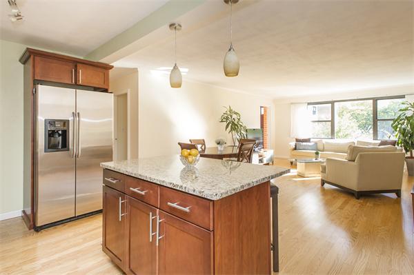 a living room with stainless steel appliances granite countertop a sink dishwasher and a dining table with wooden floor
