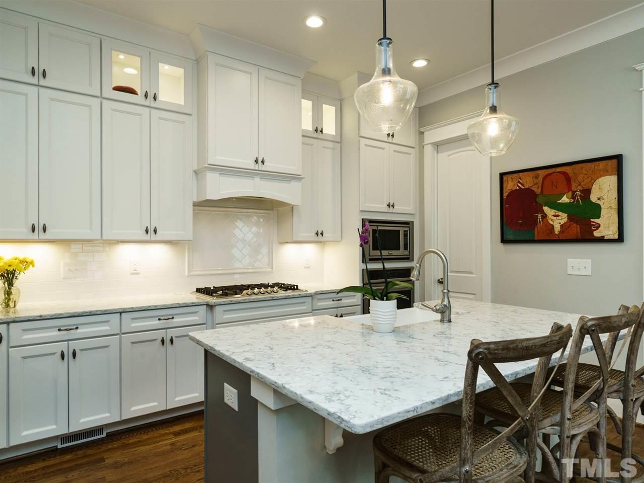 710 Virginia Avenue Raleigh, NC 27604 - Photo 5 of 25 a kitchen with kitchen island granite countertop a stove a sink a dining table and chairs with wooden floor